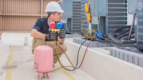 AC repair technician charging an air conditioning system with R-410a freon refrigerant.